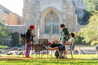 Students gathered at a table on the lawn of Cross Campus